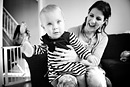 A smiling mother holds her baby as she plays. Black and white image.