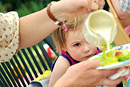 A young girl watches intently as her mother pours cream