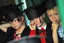 Three boys in mortar board hats take part in a play