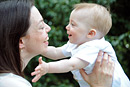 A baby reaches out to her mother as both smile