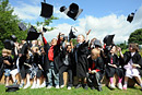 Children dressed as graduates throw their mortar boards in the air while cheering