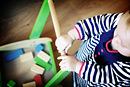 A toddler pushes a trolley of bricks, taken from above