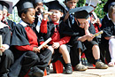 Children dressed as graduates play in the sunshine