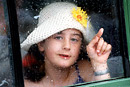 A girl chases raindrops on the window with her finger