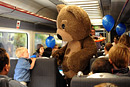 A boy meets a huge teddy bear on a train full of children