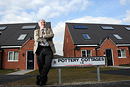 A man leans against a street sign in a street of new homes