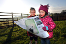 Two toddlers look at a map in a field on a cold winter morning