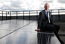 A man poses with solar panels on a rooftop