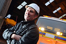 A workman in a hard hat poses with a snow plough