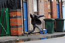 A boy tries to leap over a huge puddle