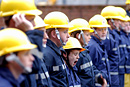 A boy in a line-up of children dressed as firemen yawns after a hard day