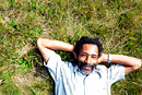 A man laying on his back on the grass, taken from above