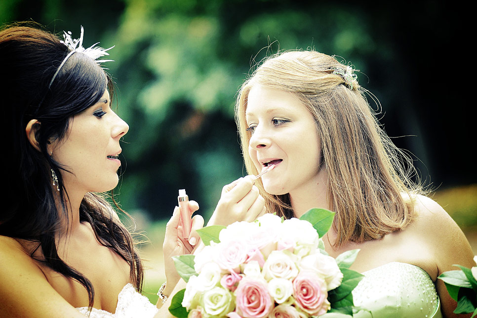 Bride adding lipgloss to the bridesmaid